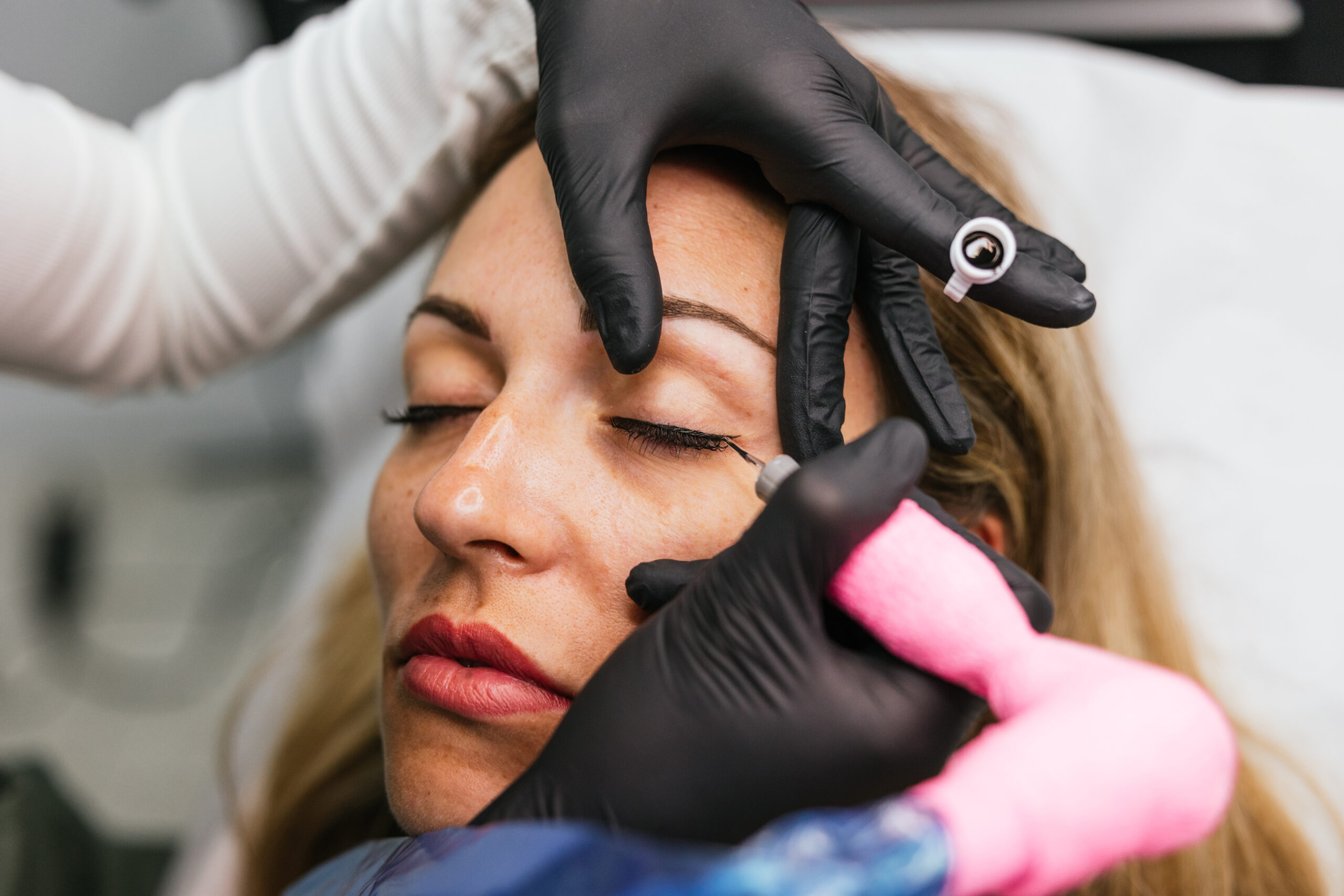Closeup view of a professional cosmetic procedure, applying permanent eyeliner through micropigmentation on a woman's eyelids in a beauty clinic - Natucci Estetica Maquillage Permanent